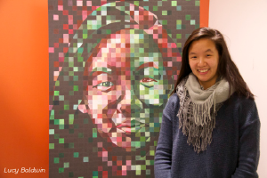 Chloe So ‘15 poses next to her “Chuck Close inspired self portrait.” 